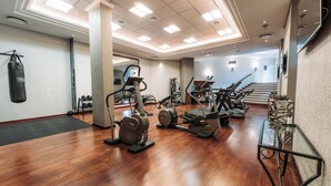 Een ruime fitnessruimte met diverse fitnessapparaten, een bokszak en een trap naar een hoger niveau.
