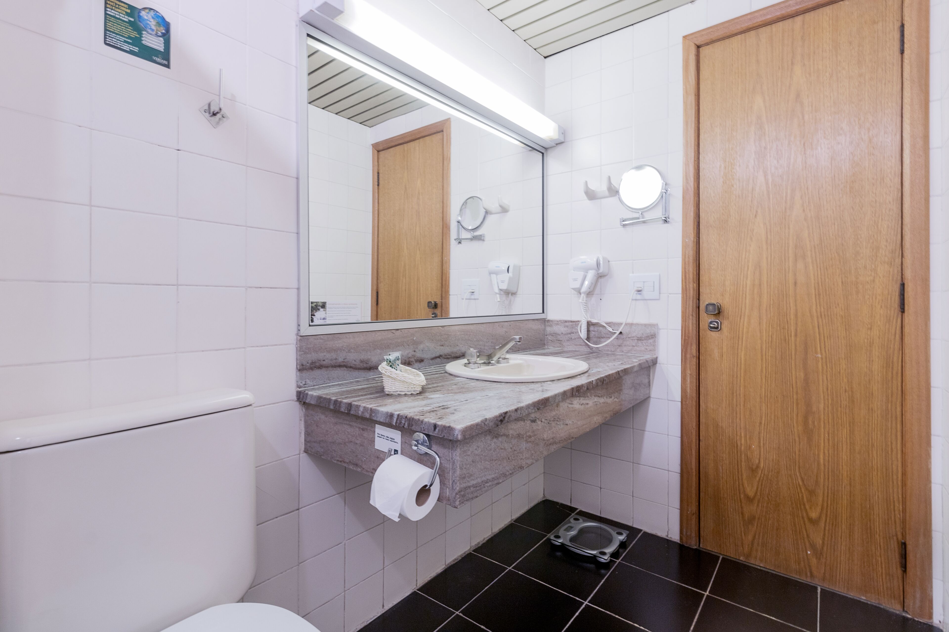 A bathroom with a marble sink, a wooden door, a mirror, and a toilet.