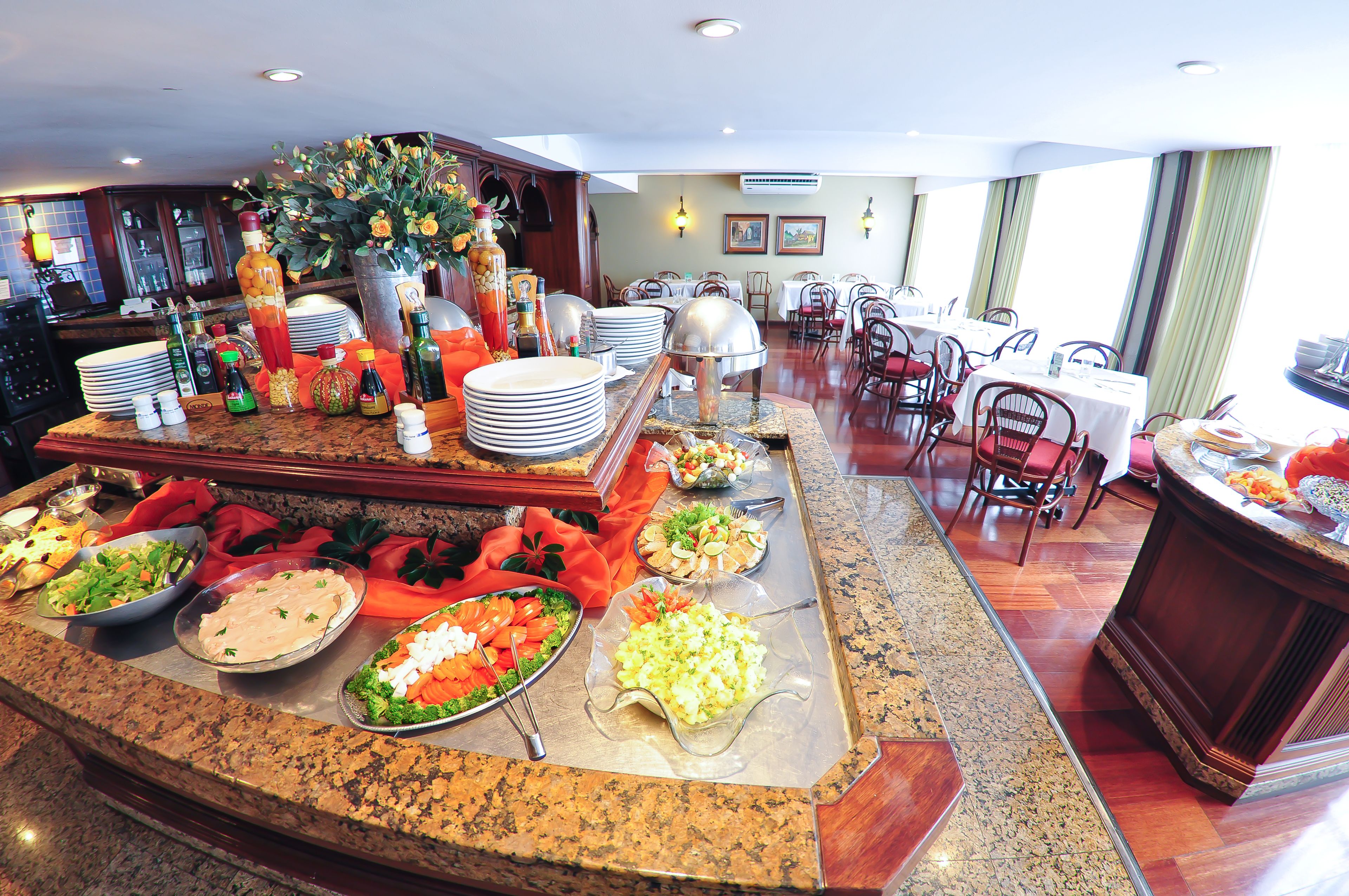 Zona de bufé con diversos platos y un comedor con mesas y sillas.