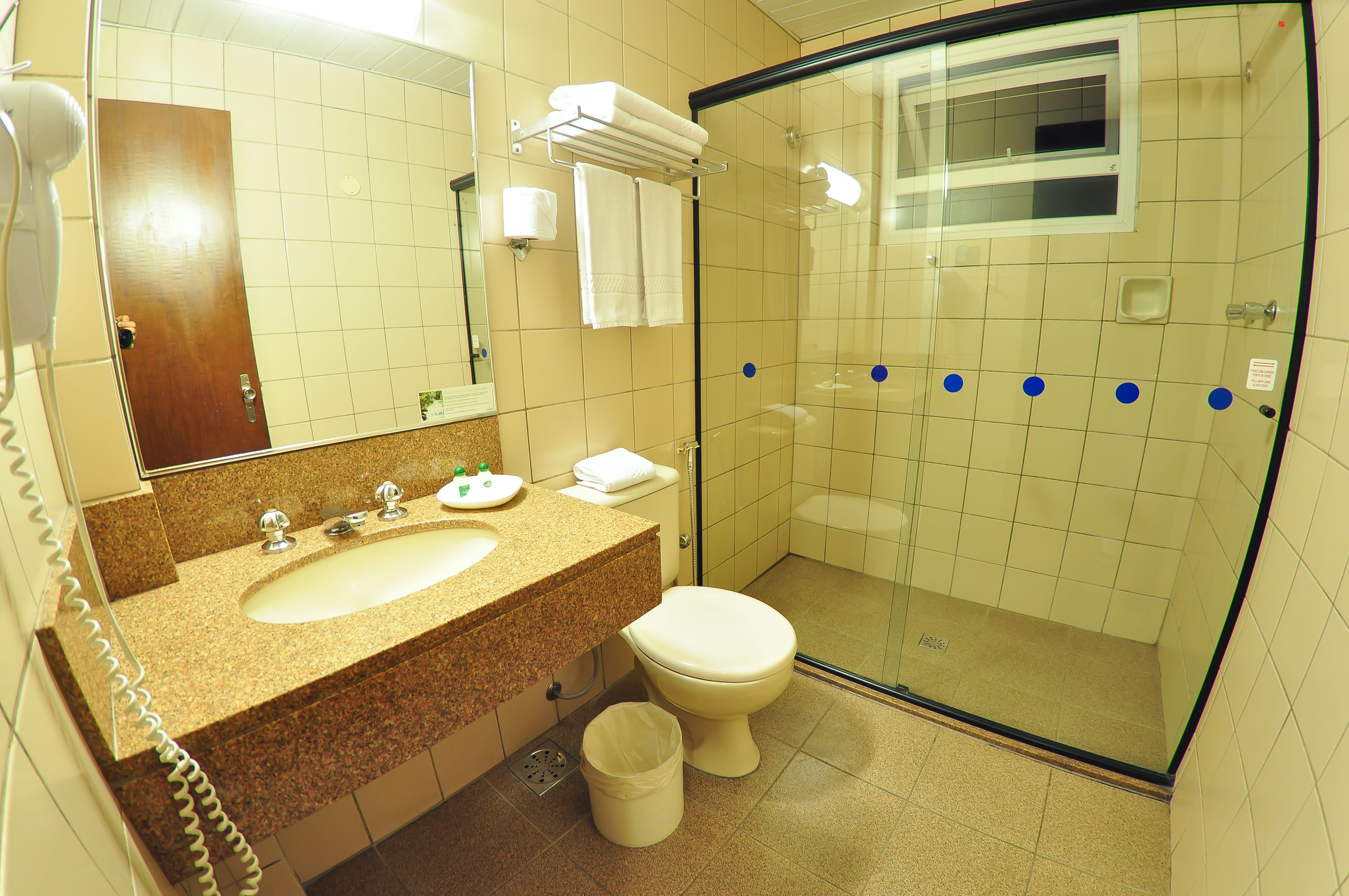 A bathroom with a sink, toilet, and a glass-enclosed shower stall.