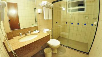 A bathroom with a sink, toilet, and a glass-enclosed shower stall.