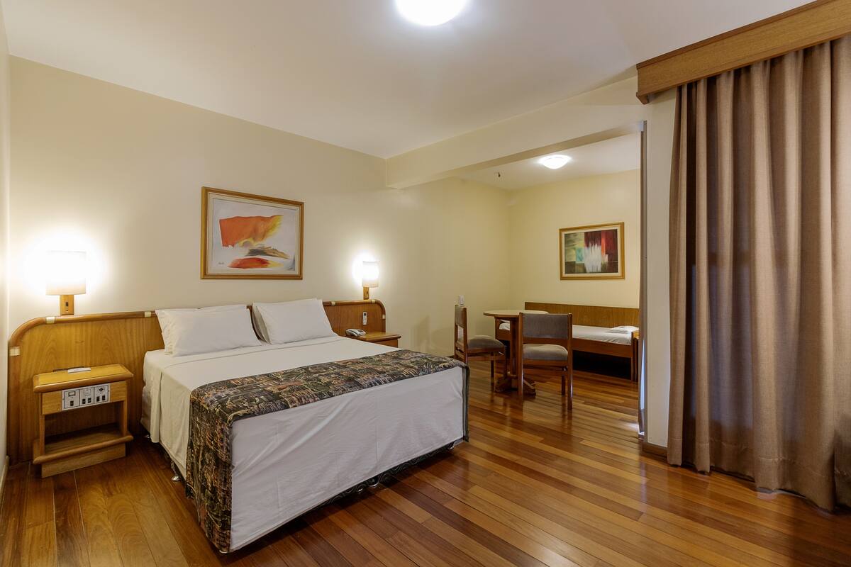 A hotel room with a bed, bedside tables, a desk, and two chairs.