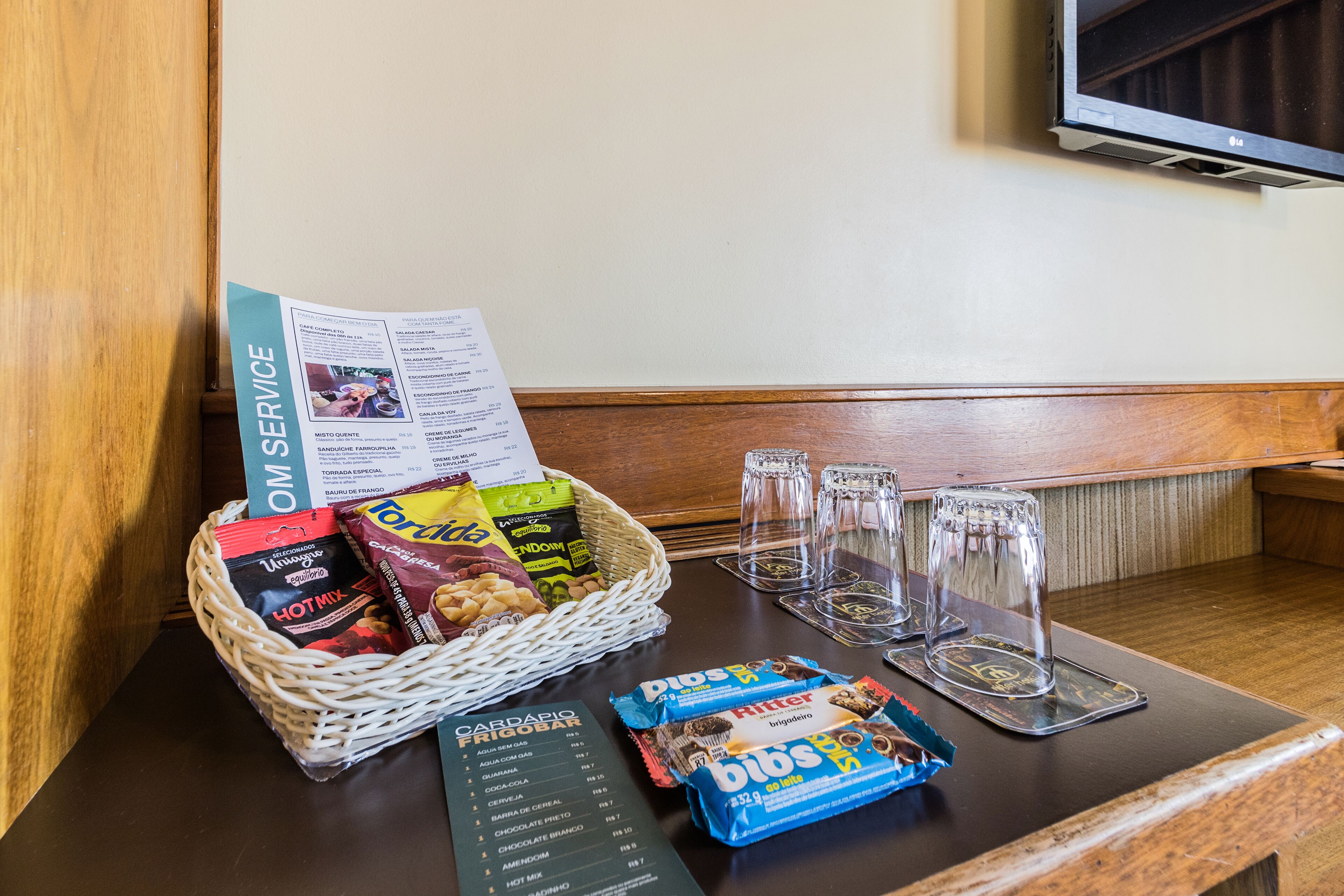 Zona de recepción de un hotel con un menú, una cesta de aperitivos y vasos sobre el mostrador.