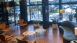 A modern lobby with wooden flooring, comfortable seating, large windows, and potted plants. - Ritter Hotéis (Porto Alegre)