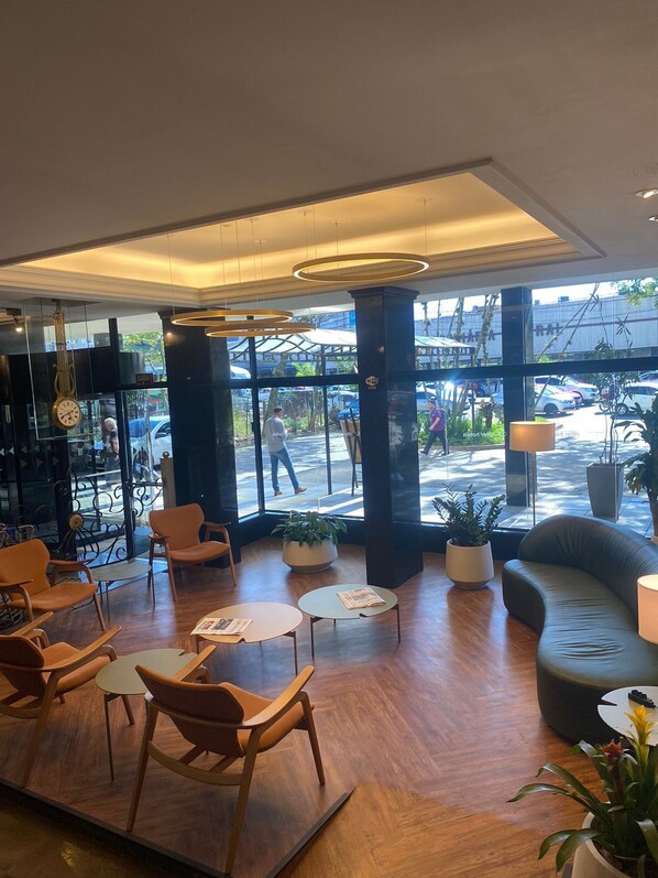 Un hall d’entrée moderne avec un plancher en bois, des sièges confortables, de grandes fenêtres et des plantes en pot.