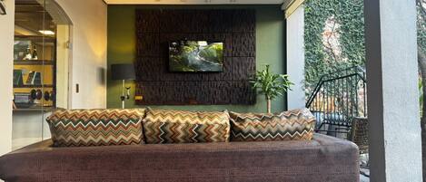 Un salón moderno con un sofá grande, cojines estampados, un televisor de pantalla plana y vistas a zonas verdes.