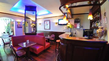 Zona de bar con muebles de madera, un rincón con asientos tipo banca y una barra con una exhibición de aperitivos.