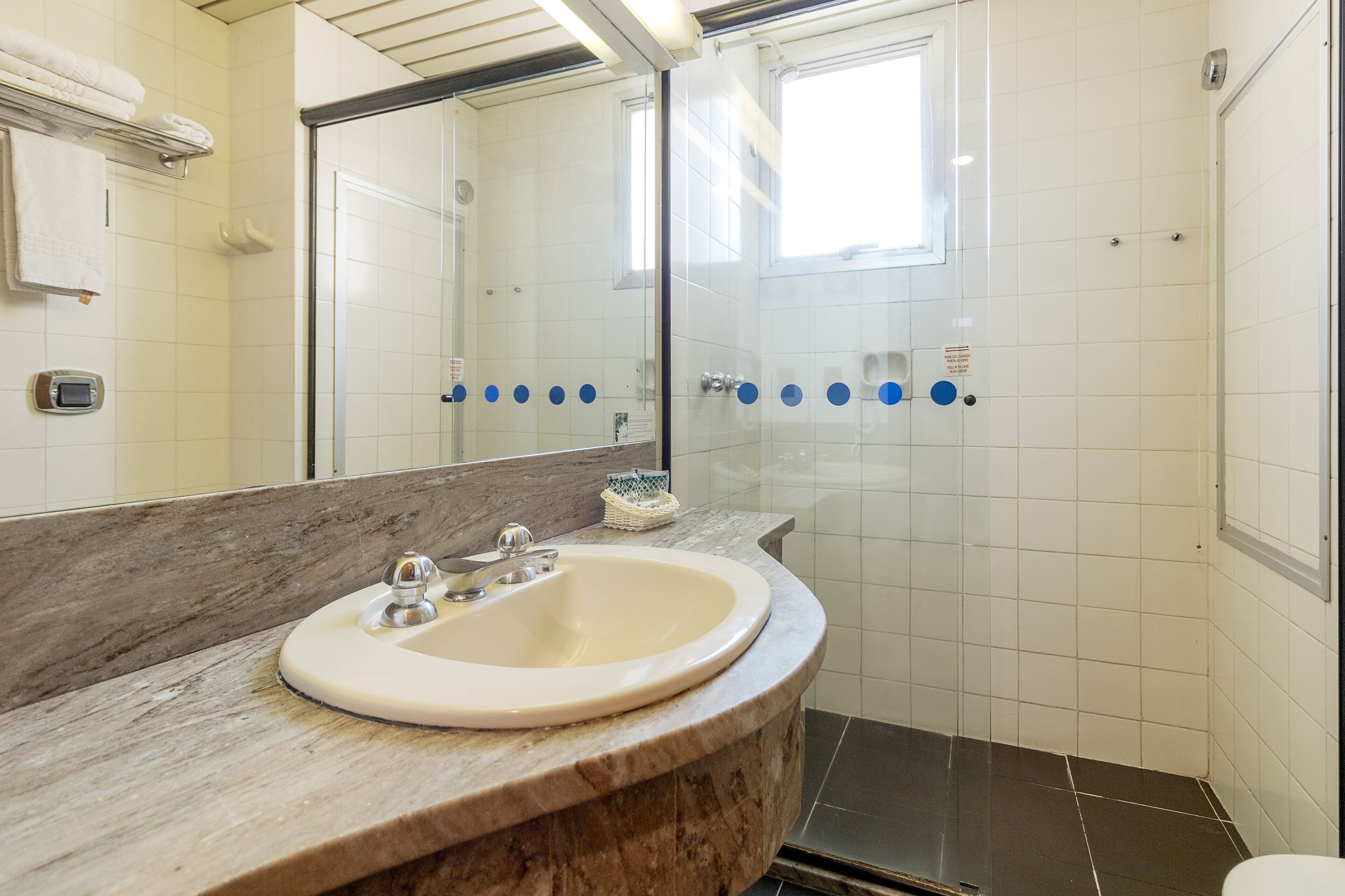 A bathroom with a marble sink, a mirror, and a glass shower enclosure.