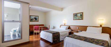 Ein Hotelzimmer mit zwei Betten, einem Schreibtisch, einem Stuhl und einem Fenster.