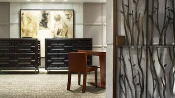 A modern interior with a geometric patterned wall, a wooden dining table, and a decorative panel with abstract branches.