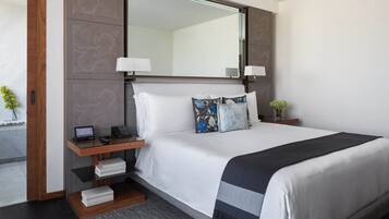 A neatly arranged hotel room with a large bed, bedside tables, a mirror, and a small side table with a lamp.