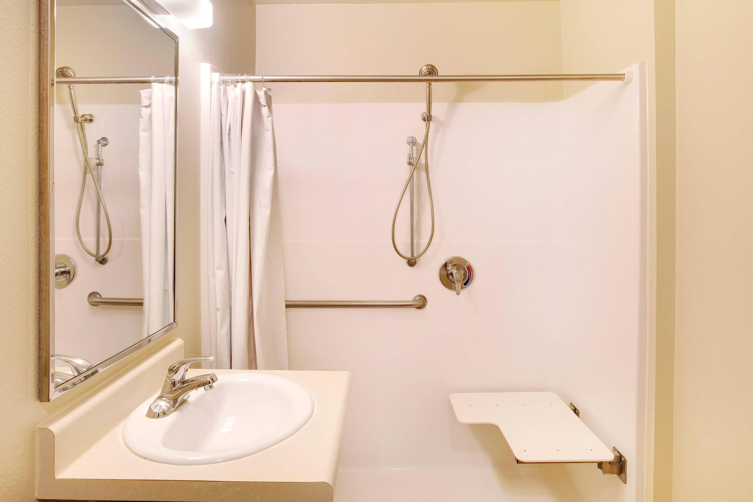 A bathroom with a white sink, a mirror, a shower with a glass door, and a towel rack.