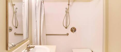 A bathroom with a white sink, a mirror, a shower with a glass door, and a towel rack.