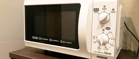 A white flat table microwave with a digital display, two power settings, and a weight scale.