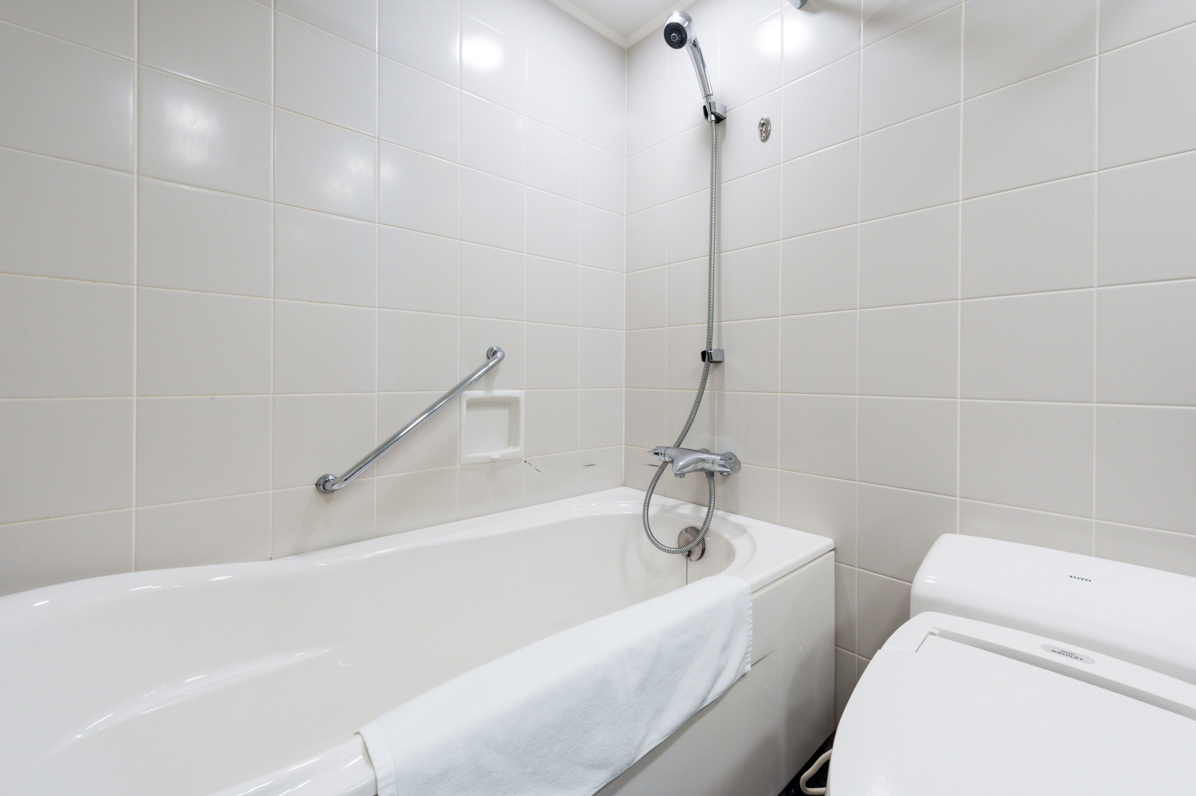 Un baño moderno con una bañera blanca, un cabezal de ducha y un inodoro.