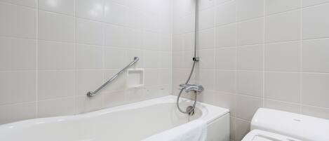 Un baño moderno con una bañera blanca, un cabezal de ducha y un inodoro.