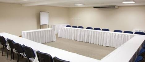Un salón de conferencias con una larga mesa, sillas y una pizarra.