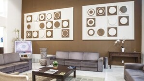 A modern living room with a grey sofa, a coffee table, and a TV. There are two wall art pieces above the sofa. - Tri Hotel Executive Caxias (Caxias do Sul)