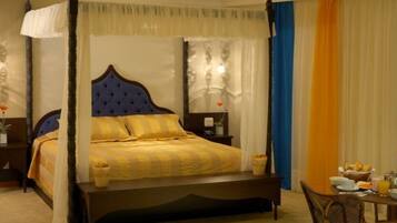 A four-poster bed with a canopy, a bedside table with a lamp, and a breakfast setup on the right.
