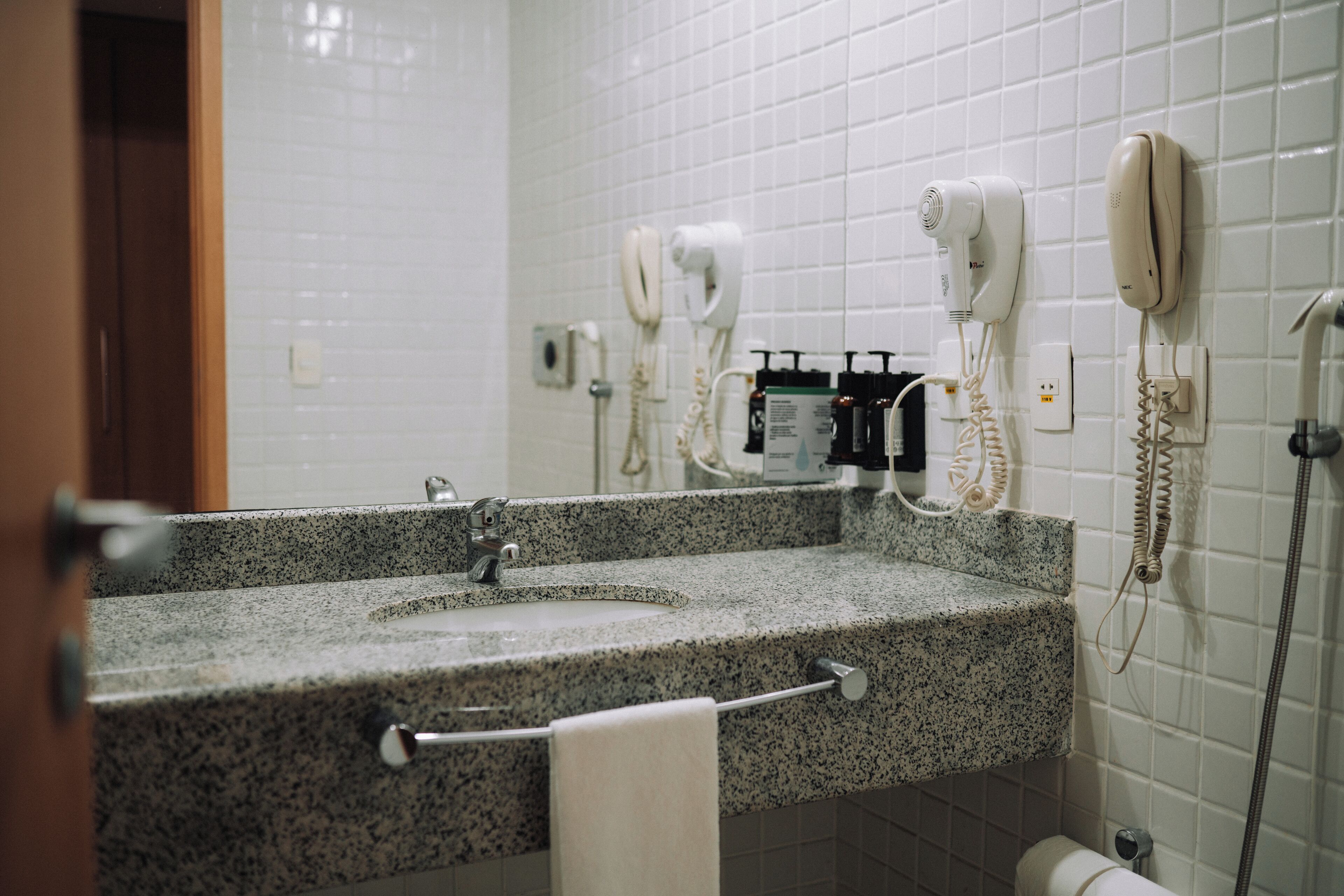 Un baño con encimera de granito, dos lavamanos, un perchero y un espejo.