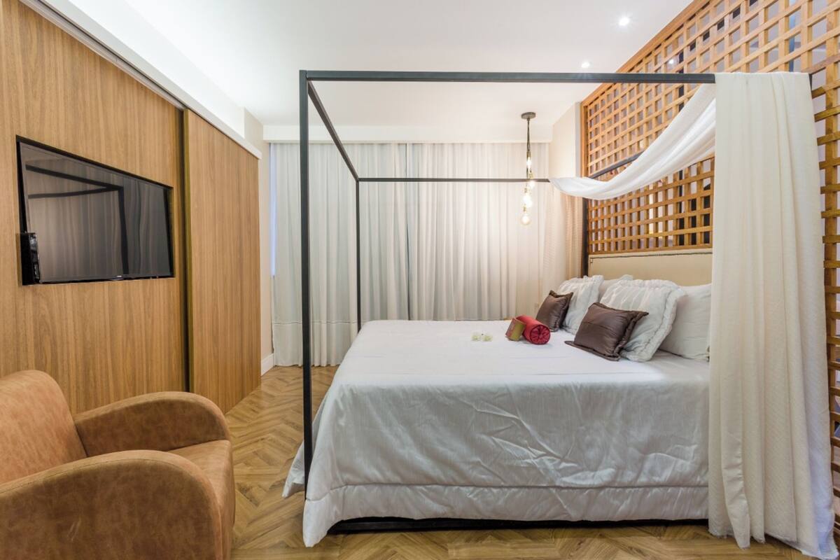 Ein modernes Hotelzimmer mit einem großen Bett, einem an der Wand befestigten Fernseher und Holzboden.
