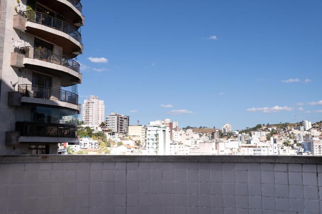 A high-rise building with multiple balconies and a cityscape in the background.