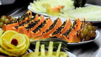 Diversa variedad de frutas cortadas, incluyendo papaya y piña, sobre una mesa de buffet.