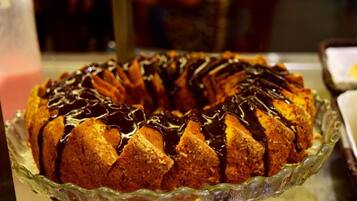 Un pastel Bundt con glaseado de chocolate sobre un pedestal de vidrio.