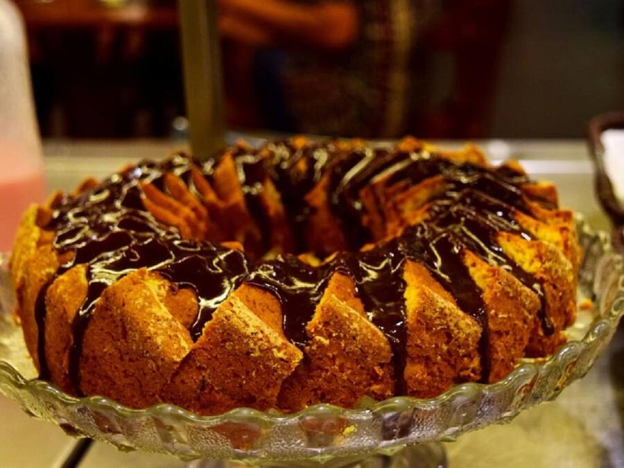 Un pastel Bundt con glaseado de chocolate sobre un pedestal de vidrio.