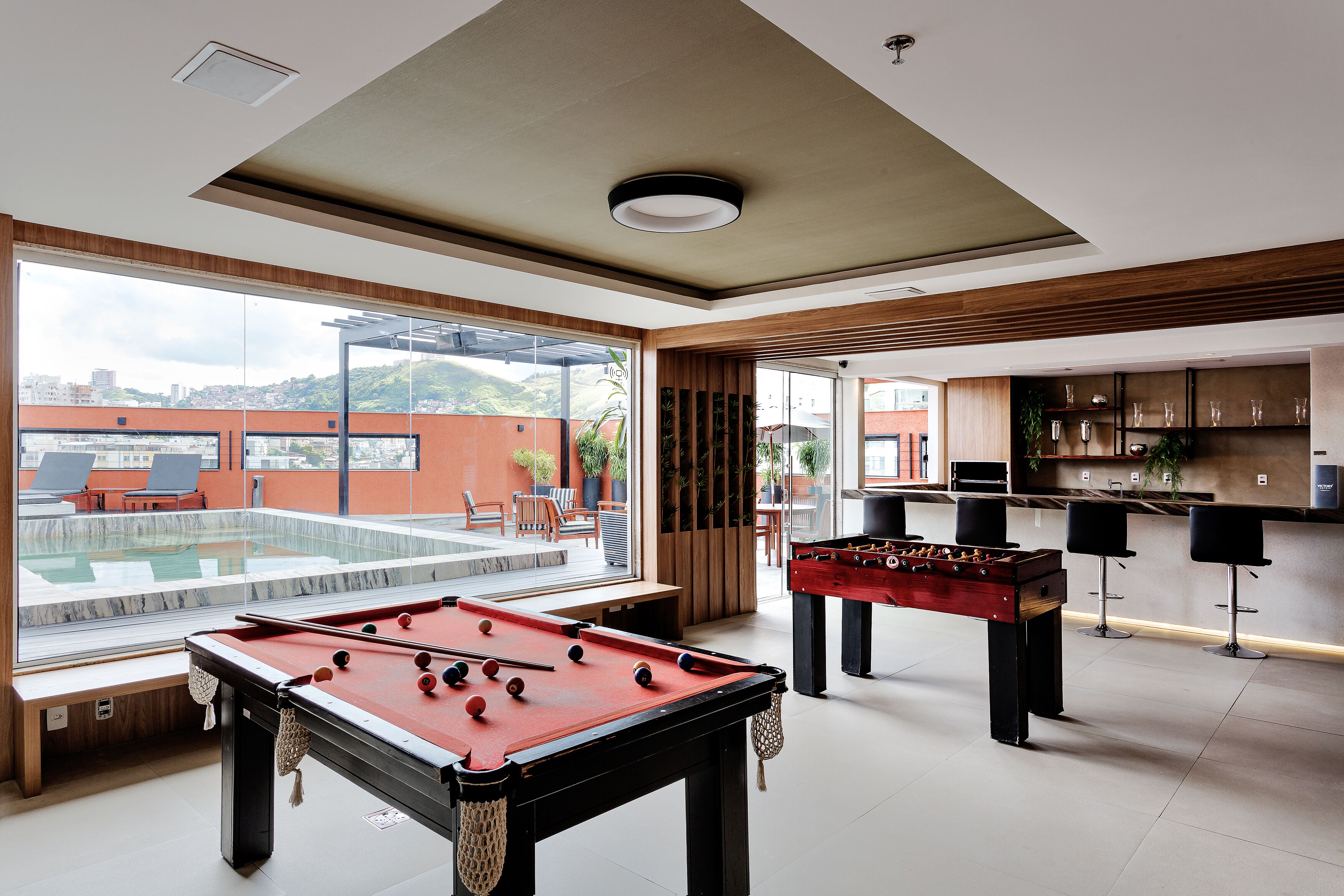Een moderne binnenzwembadruimte met een tafelvoetbaltafel en een bar met zitplaatsen.