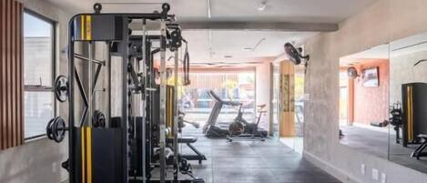 A gym with weightlifting equipment, benches, and a treadmill.