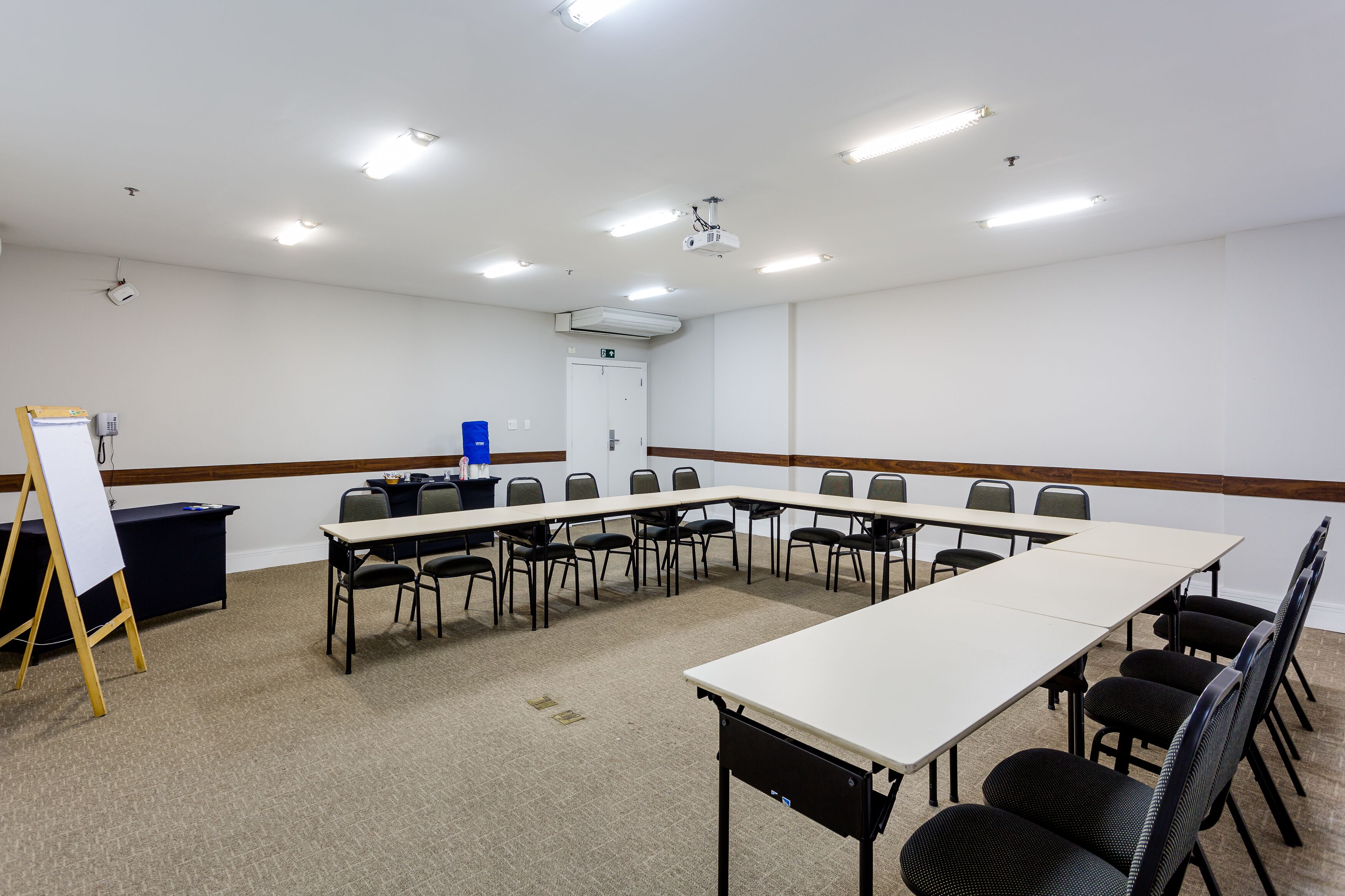A conference room with a long table, chairs, a whiteboard, and a projector.