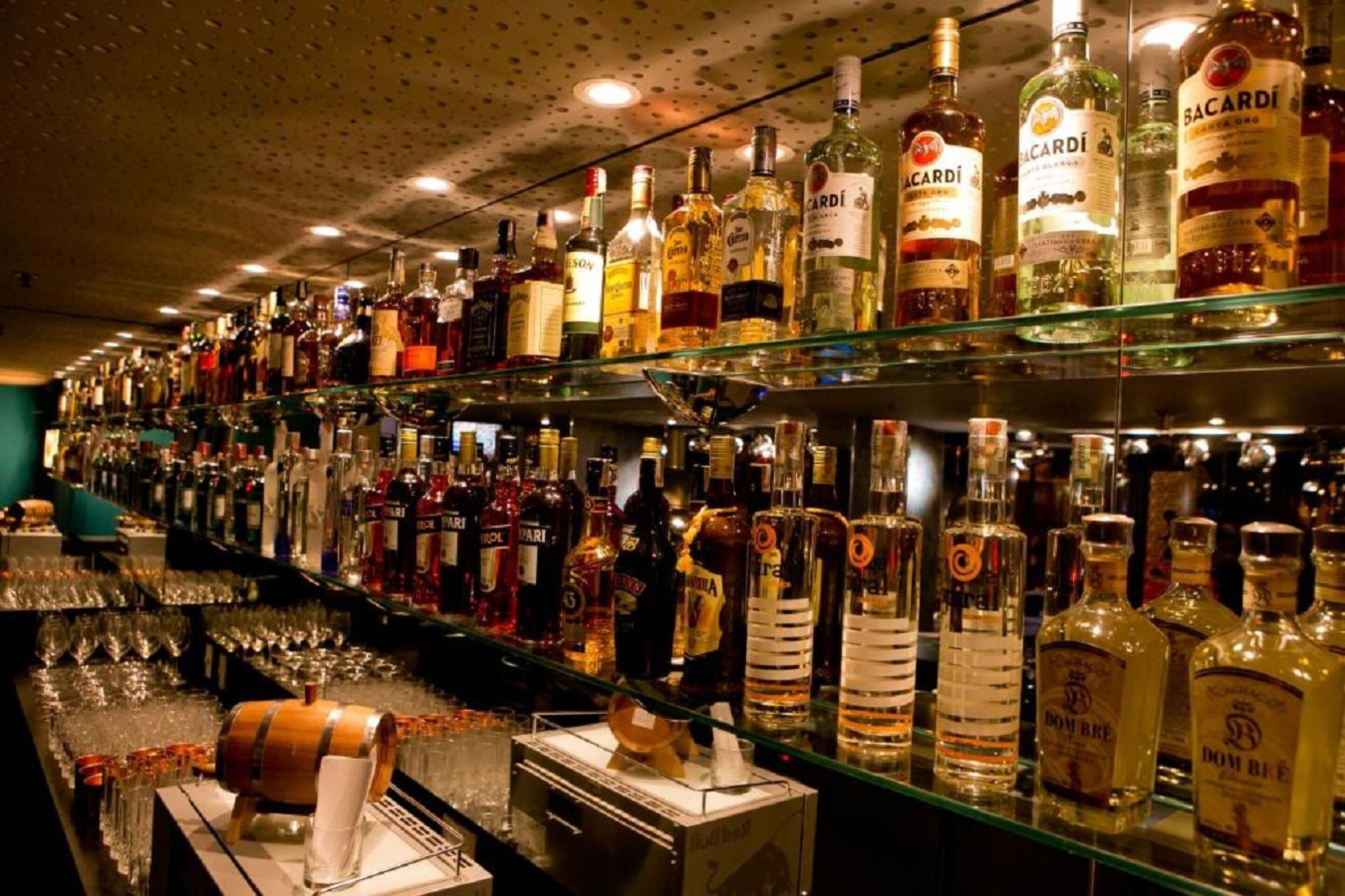 Un bar dont les étagères sont remplies de différentes bouteilles d’alcool.