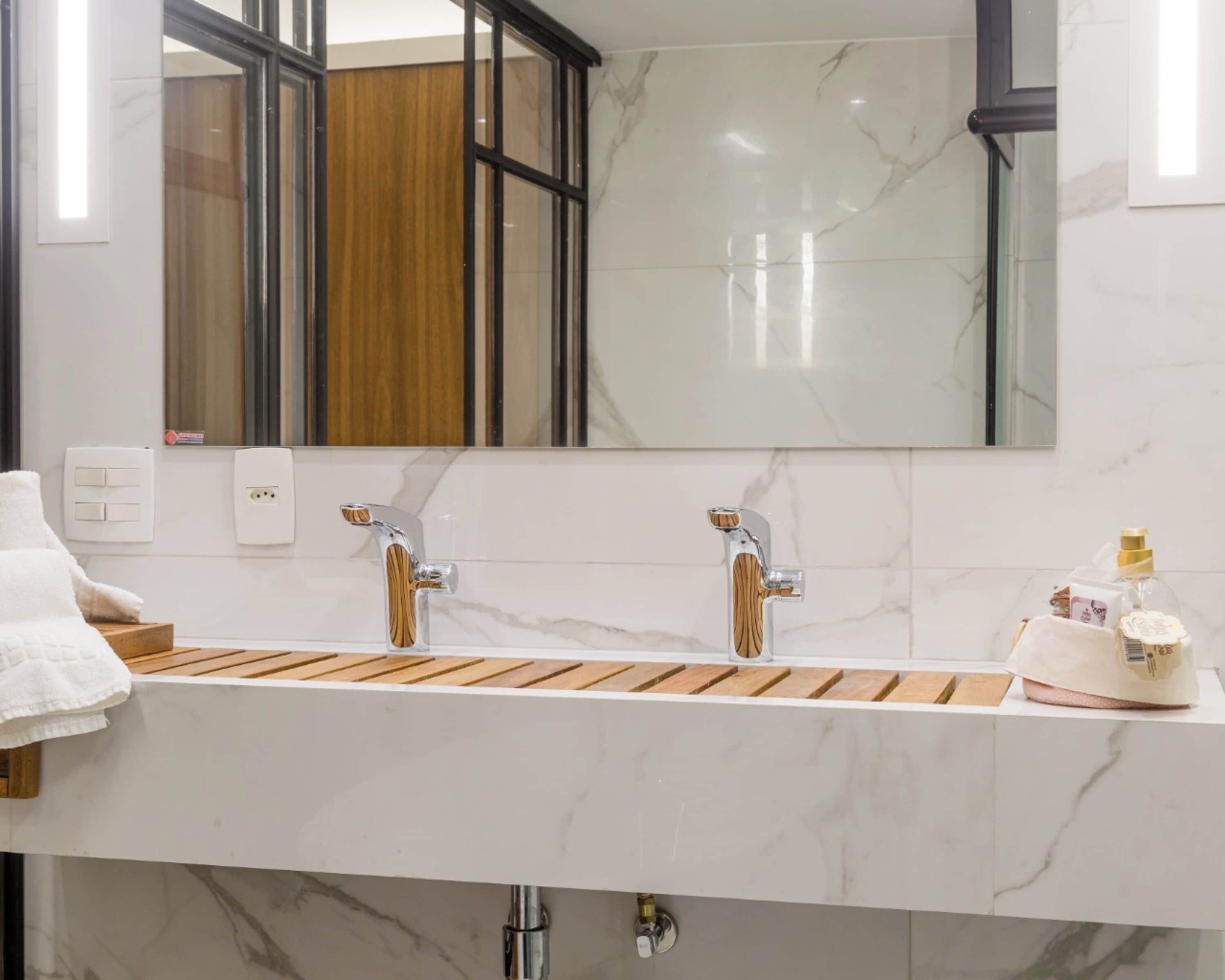 Une salle de bain moderne avec un lavabo en marbre blanc, deux robinets chromés et un meuble-lavabo en bois.