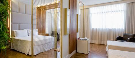 Une chambre d’hôtel moderne équipée d’un grand lit, d’un lit plus petit, d’un bureau et d’un coin salon.
