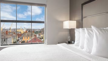 A hotel room with a large window offering a view of buildings and cranes outside.
