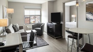 Une chambre d’hôtel moderne équipée d’un téléviseur à écran plat, d’une table à manger, d’un canapé et d’un fauteuil.