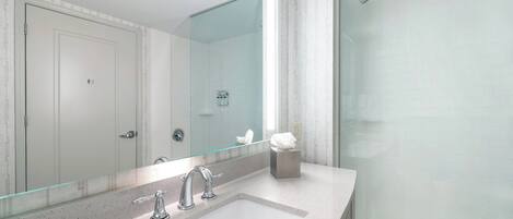 A modern bathroom with a large mirror, a sink, and a shower.