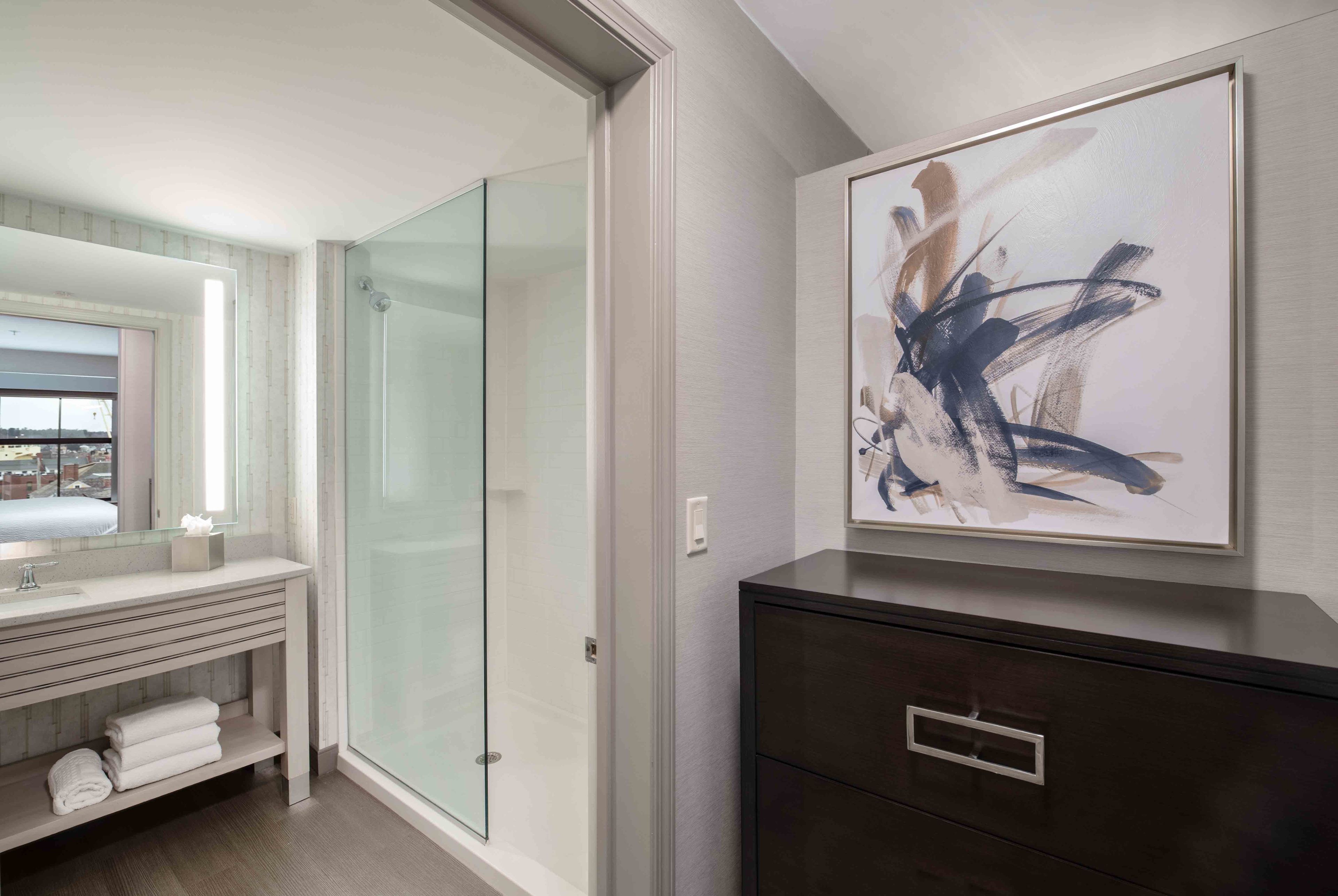 A modern bathroom with a glass shower, a vanity with a mirror, and a dark cabinet.