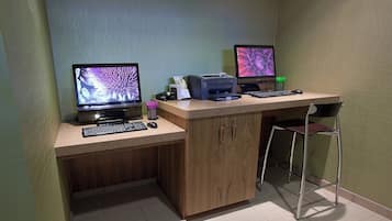 Ein kleiner Büroraum mit zwei Computern, einem Drucker, einer Tastatur, einer Maus und einem Stuhl.