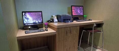 A small office space with two desktop computers, a printer, a keyboard, a mouse, and a chair.