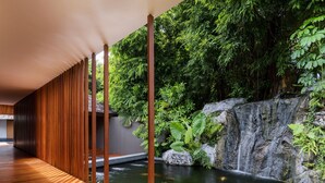 A wooden deck leading to a koi pond with a waterfall, surrounded by lush greenery. - Renaissance Phuket Resort & Spa (Mai Khao)