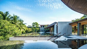 A modern resort with a clear pool, lush greenery, and contemporary architecture.