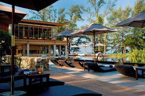 Una piscina al aire libre, sombrillas, sillones reclinables de piscina