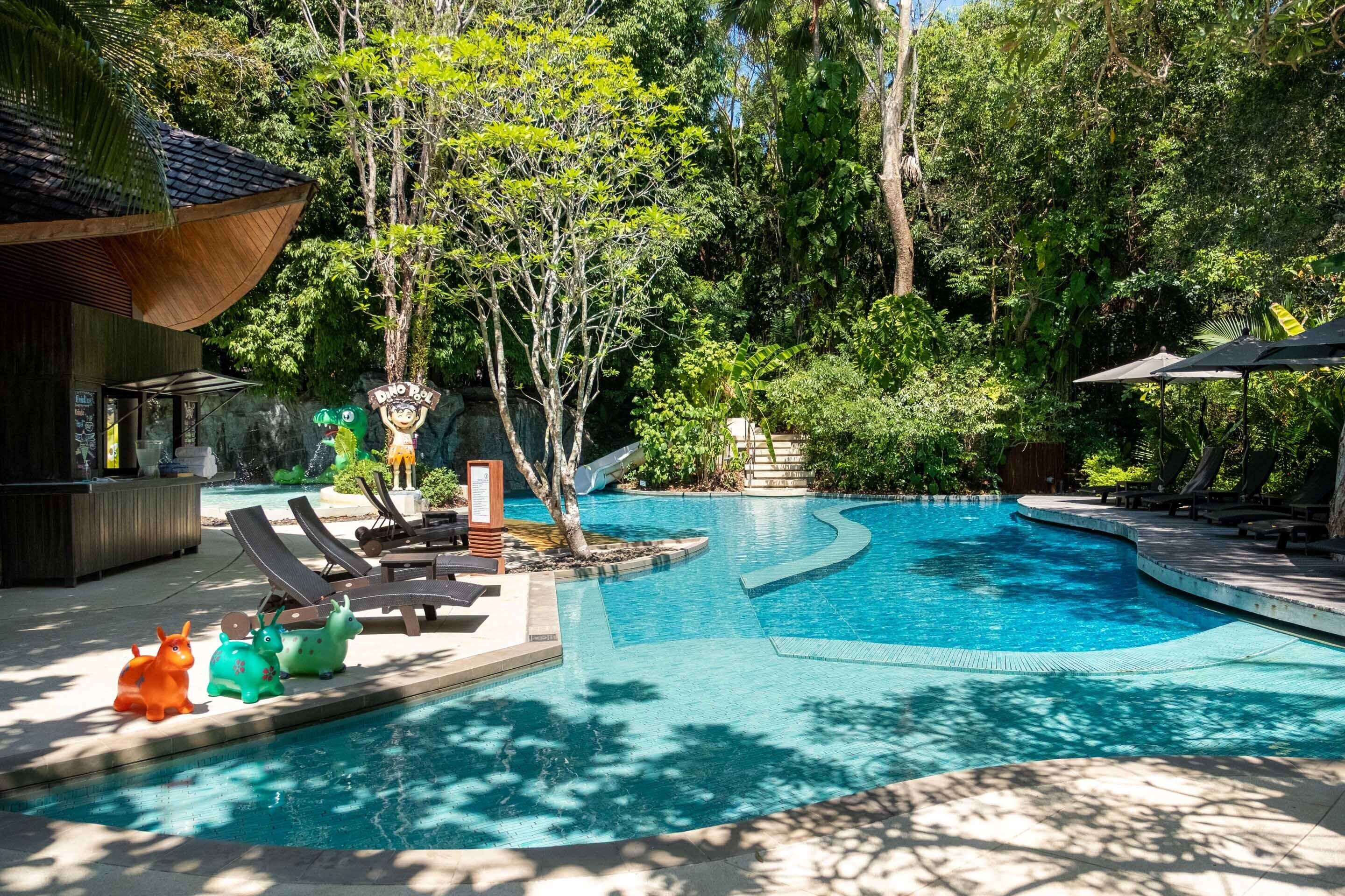 Una piscina al aire libre, sombrillas, sillones reclinables de piscina