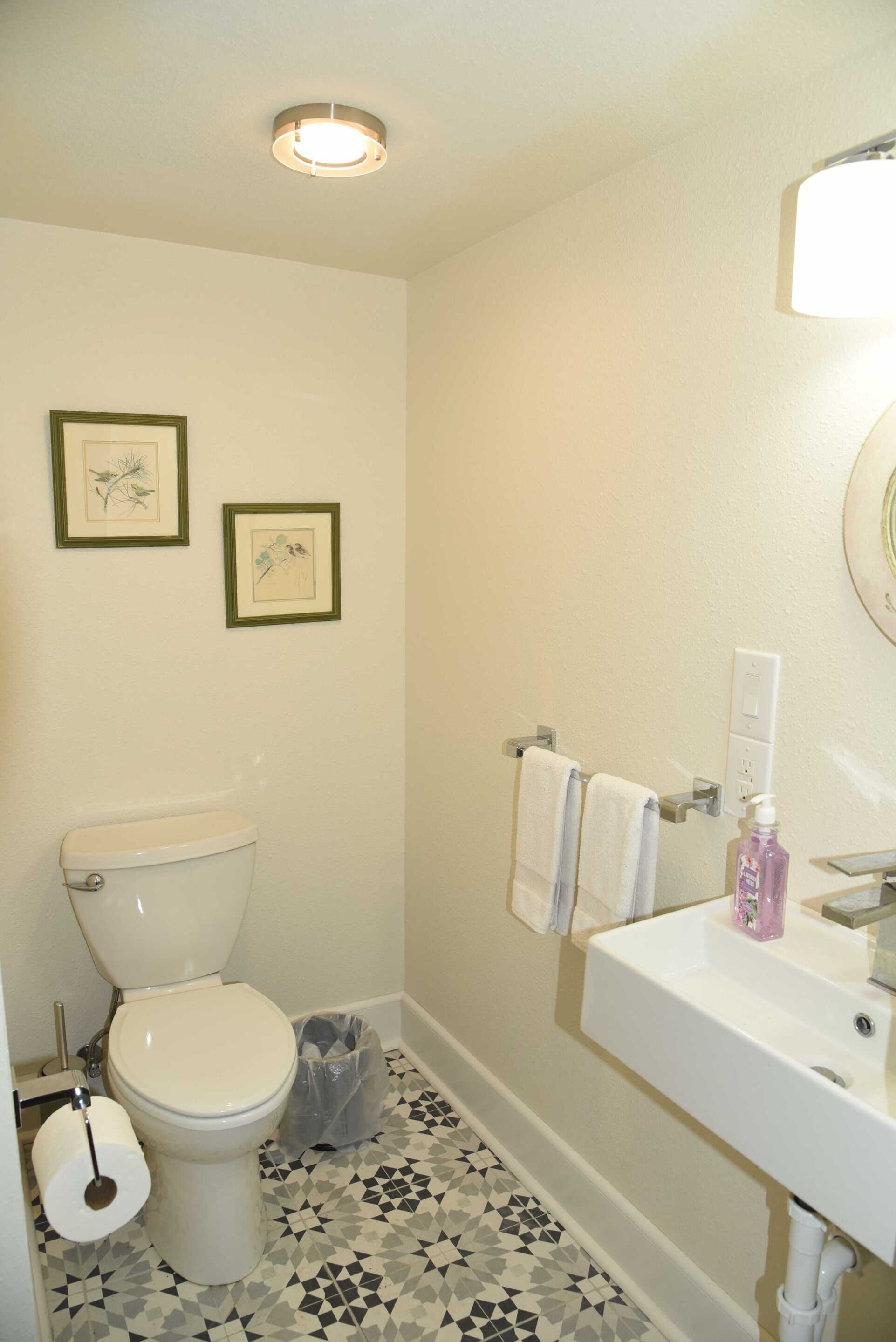Een badkamer met toilet, wastafel en twee foto's in lijsten aan de muur.