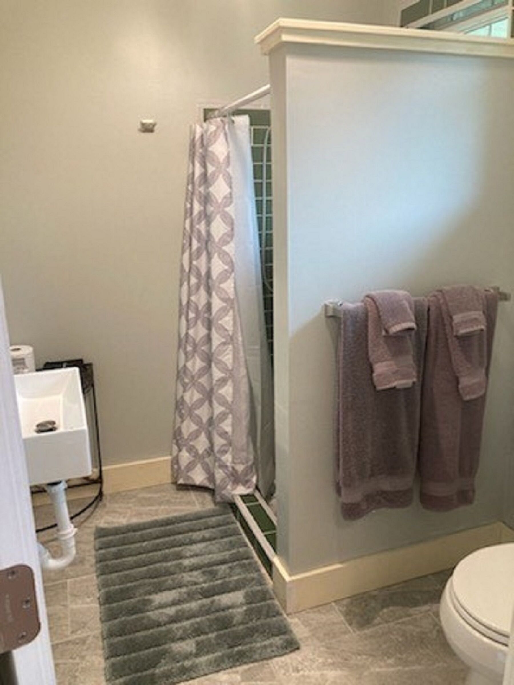 A bathroom with a shower, a toilet, and a sink.