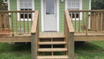 Una casa de un piso con un porche delantero y una escalera de madera que lleva a la puerta.