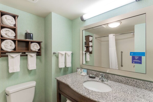 Un baño con lavamanos, espejo, toallero y retrete.