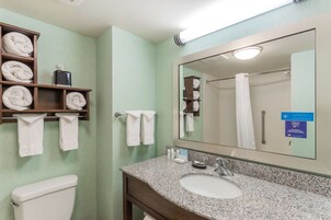 Un baño con lavamanos, espejo, toallero y retrete.